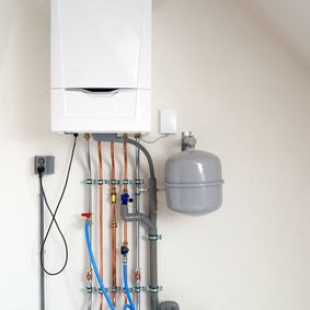 Ballon d'eau chaude et tuyaux accroché contre un mur