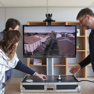 3 personnes en train de faire de la planification urbaine autour d'une table numérique qui modélise la ville en 3D